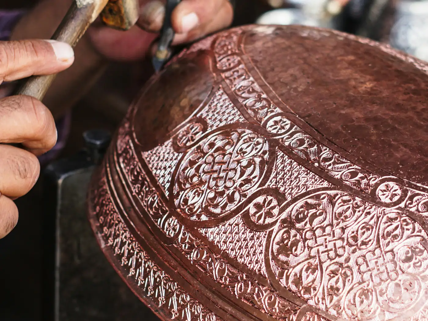 An Indian craftsman engraving a metal bowl by hand