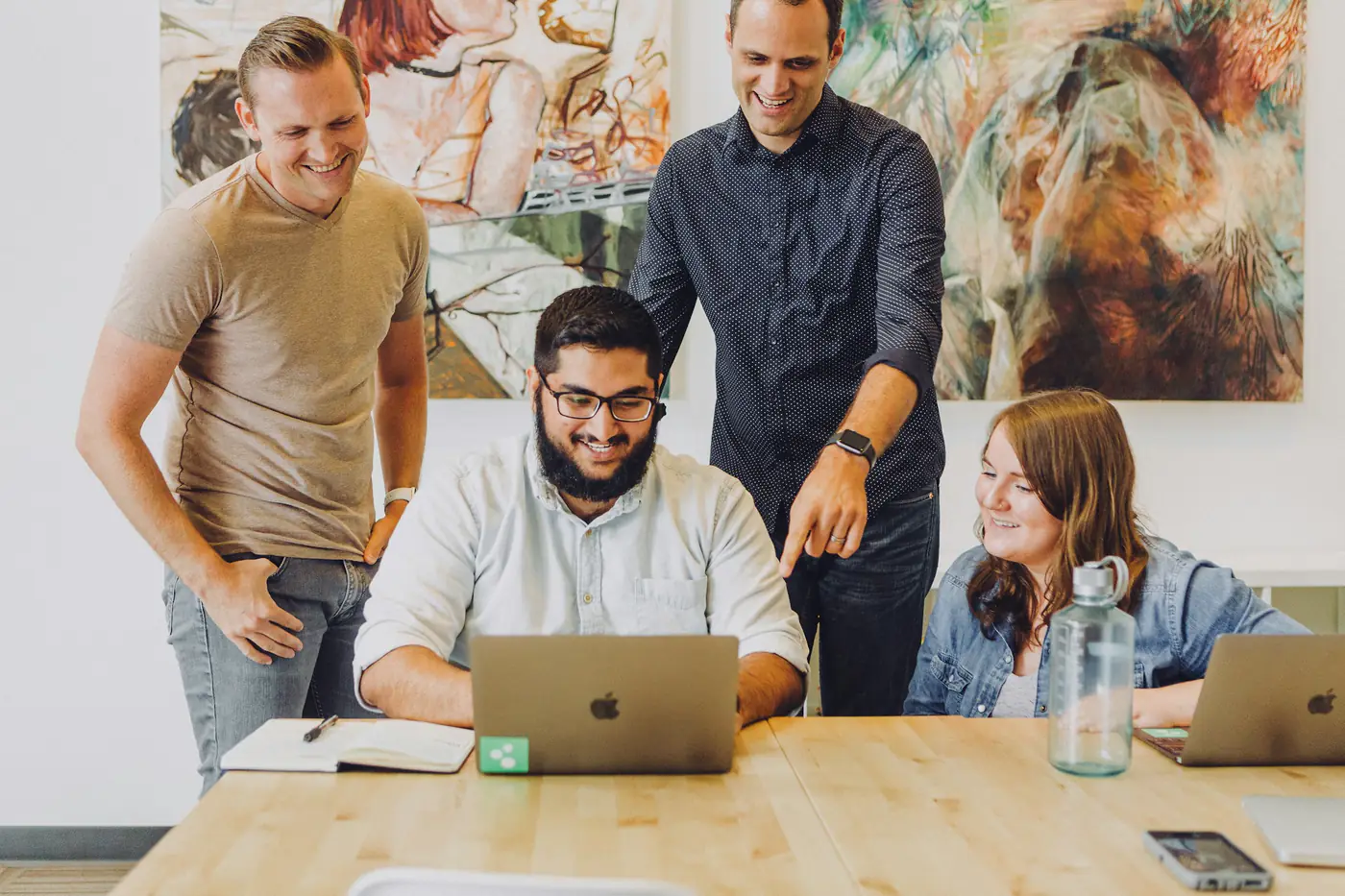 A team reviewing work together around a laptop
